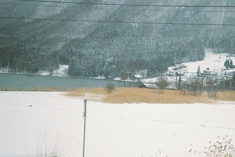 雪の積もった湖畔と山の裾野が映っている雪の日の写真。